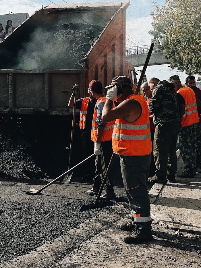 Construction workers in Vladivostok repairing roads with a dump truck unloading asphalt.